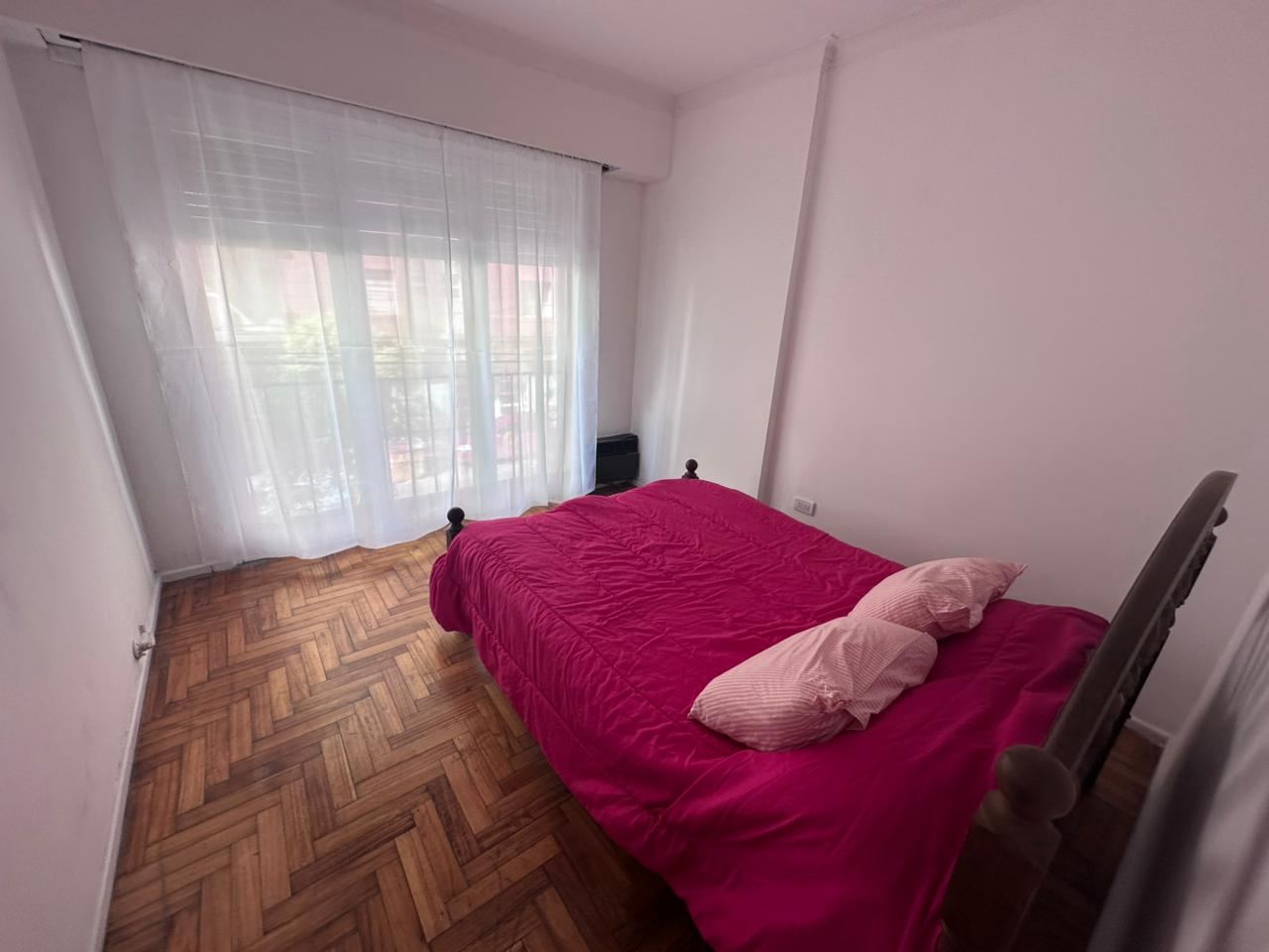 El dormitorio con el ventanal y las cortinas al frente