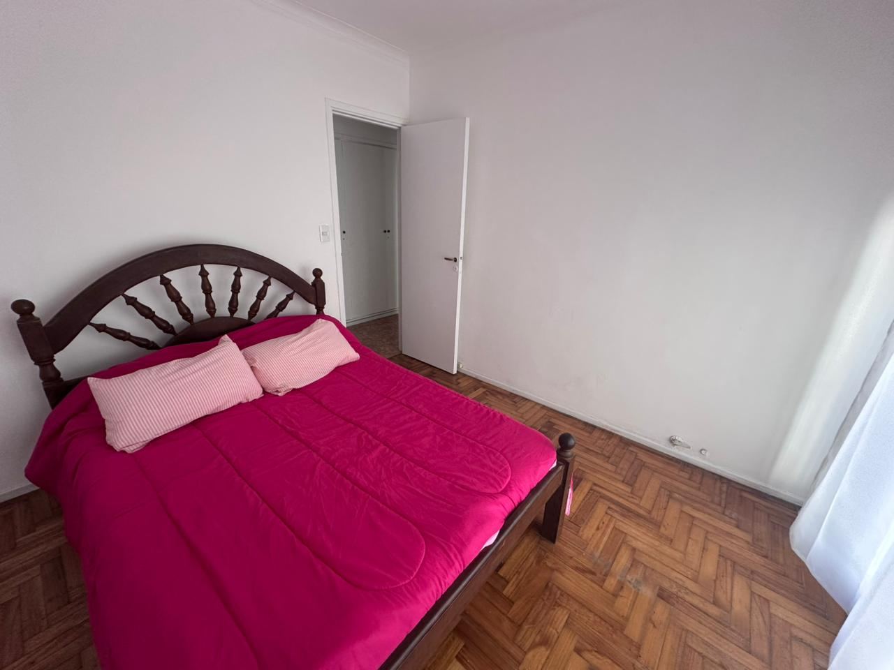 El dormitorio hacia la puerta, con el piso de parquet espinado
